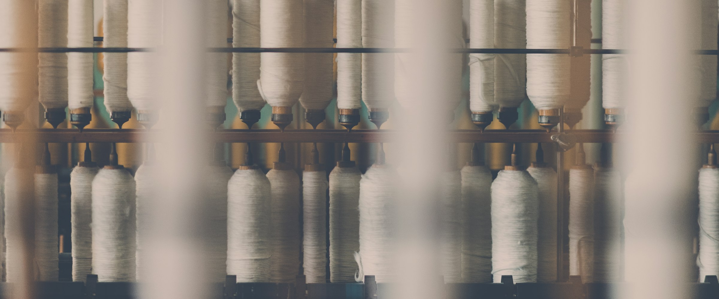 Parallel sportswear sewing lines on one production floor, operators with visible faces and hands working side by side