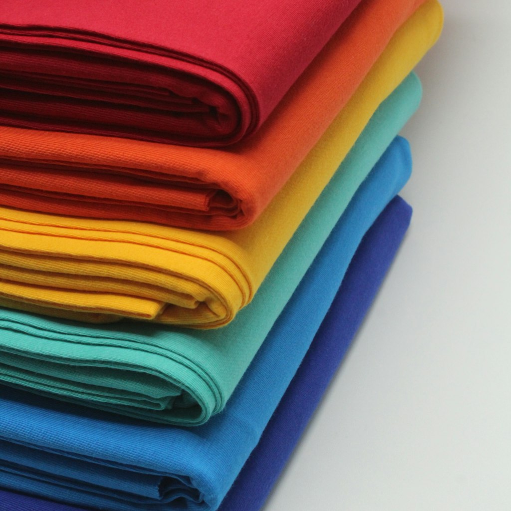 A stack of folded technical knit fabric in several colourways