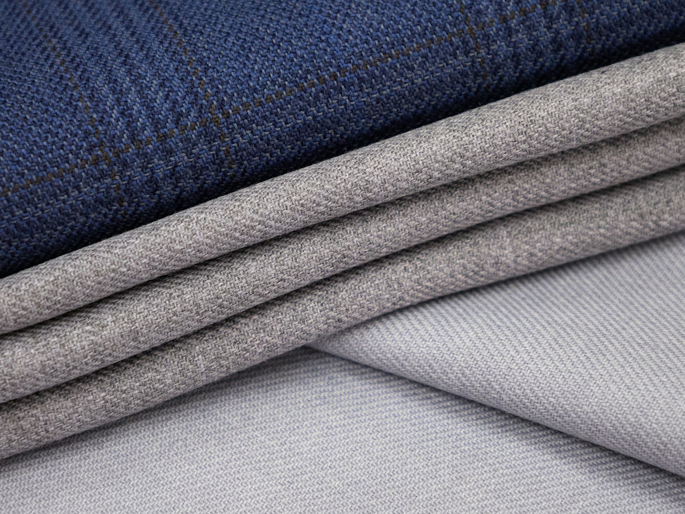 Three folded lengths of navy and grey garment cloth stacked together