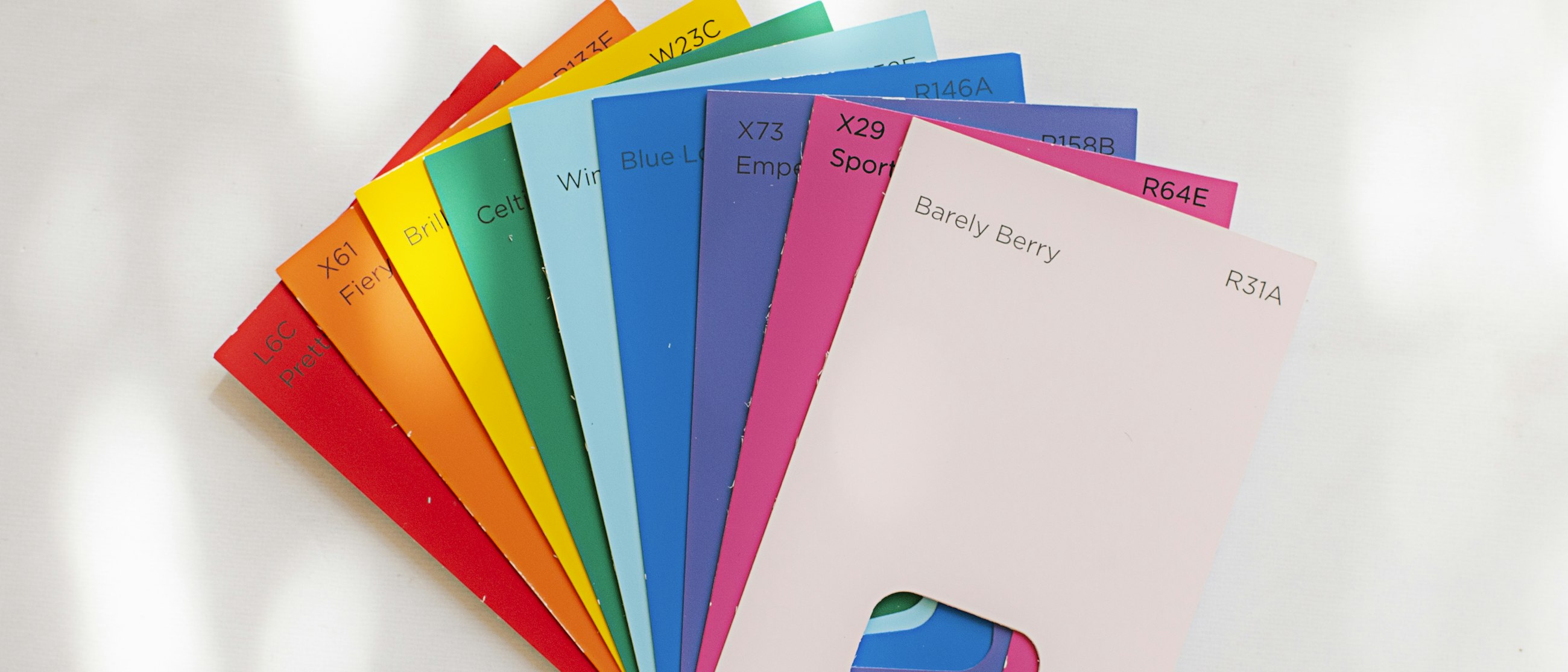 A fan of color reference cards — colors are supplied as coded references or defined builds, then matched against fabric at sampling