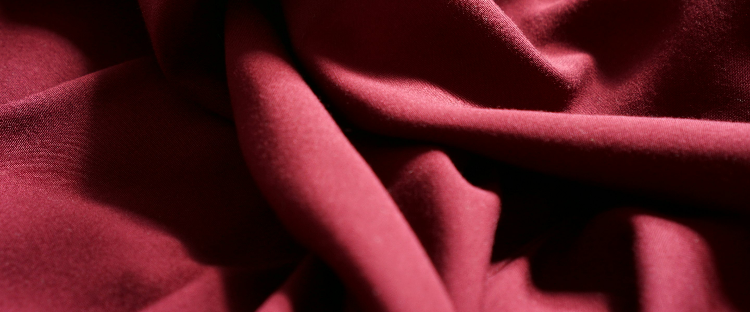 Deep crimson garment fabric falling in draped folds
