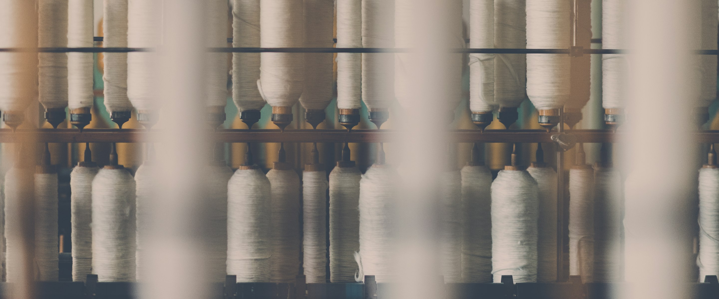 A rack of thread cones on a factory floor, held out of focus