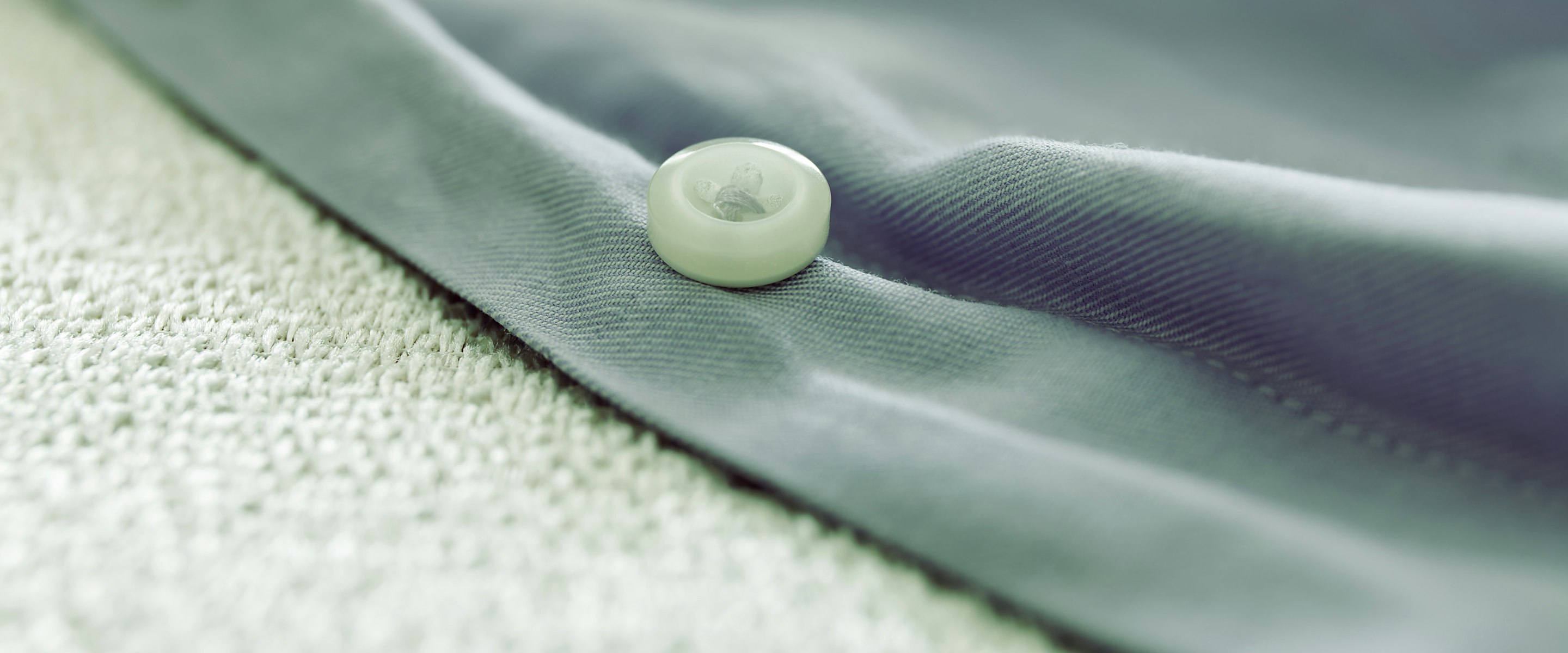 Macro of a stitched garment placket with a single plain button