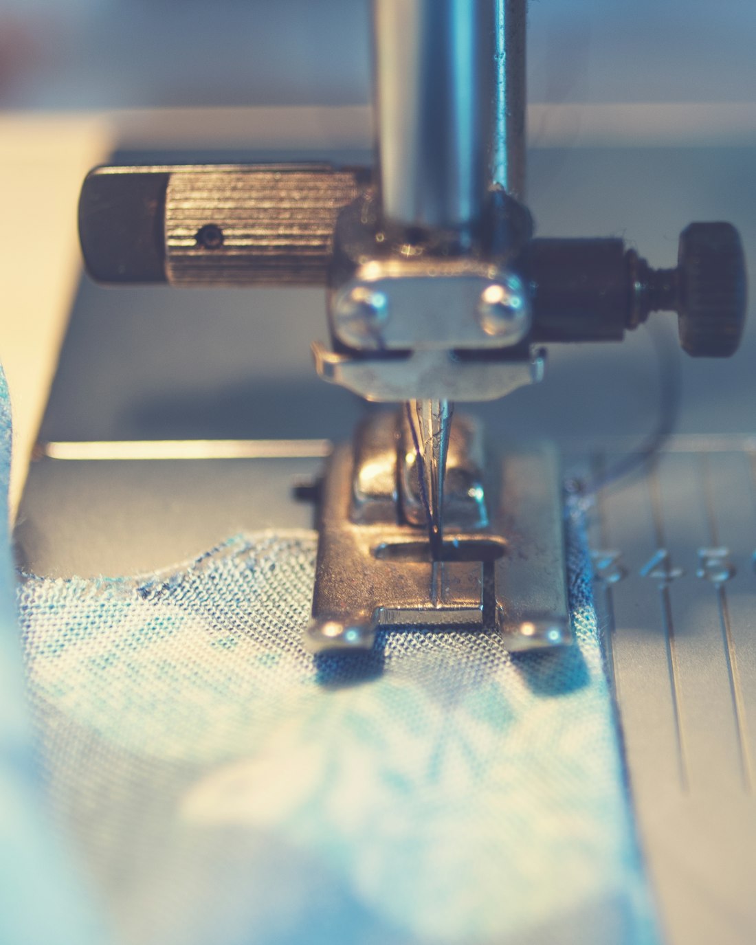 Sewing machine needle mid-stitch on fabric, production in progress