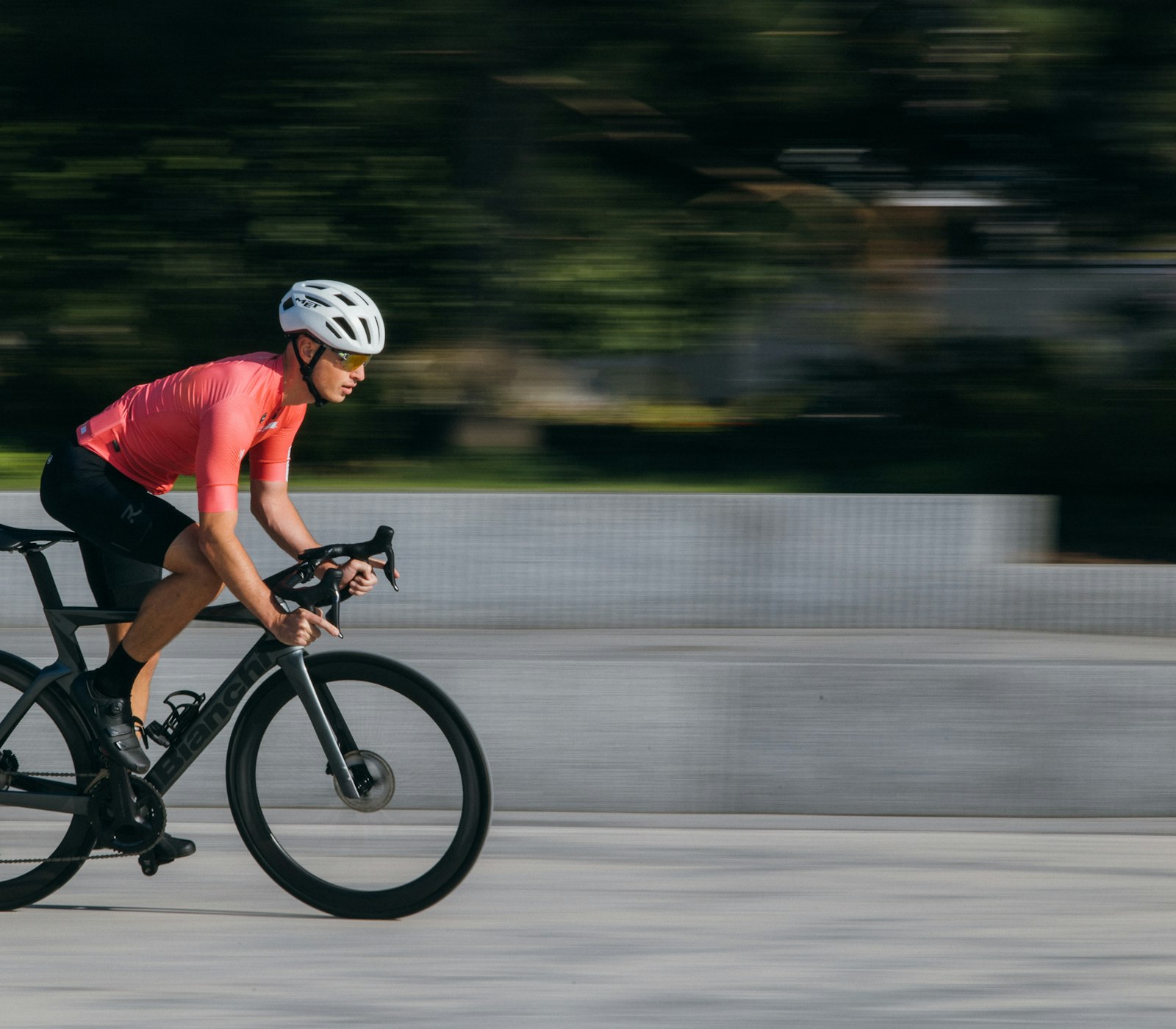 Road cyclist riding in forward-leaning race posture on a paved road in daylight