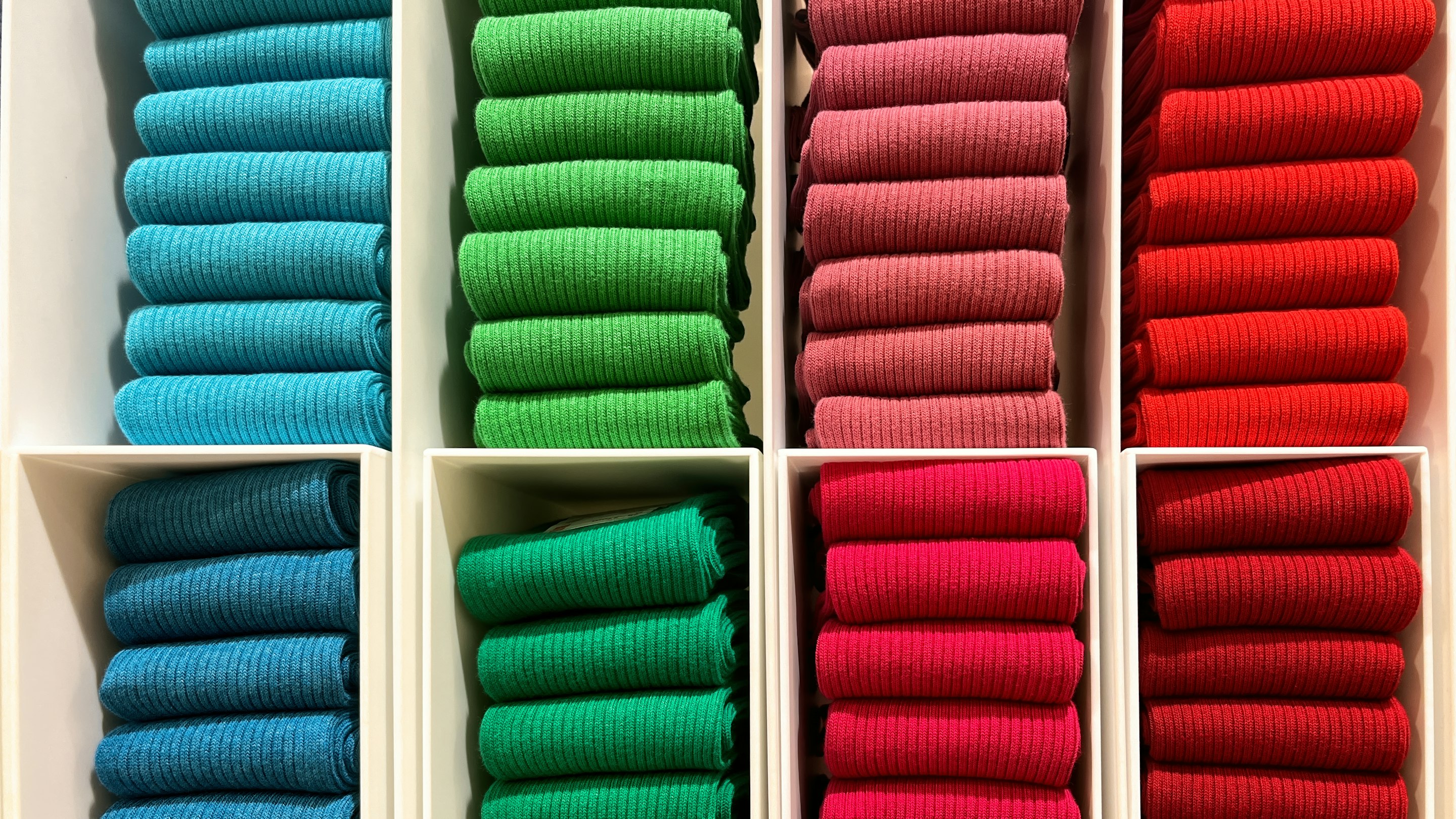 Folded garments stacked in distinct colorways on shelving