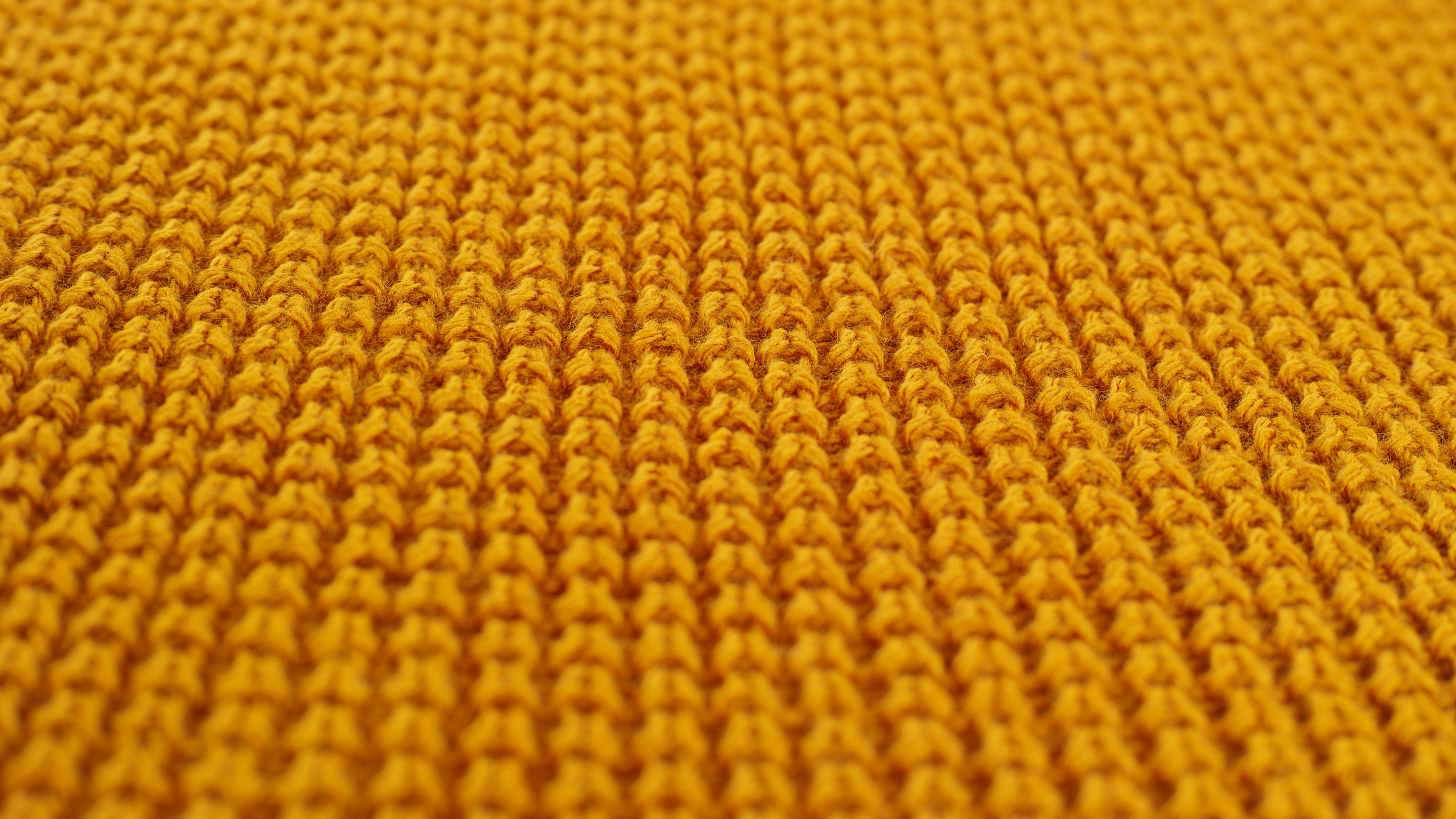 Macro close-up of mustard-yellow knit fabric texture