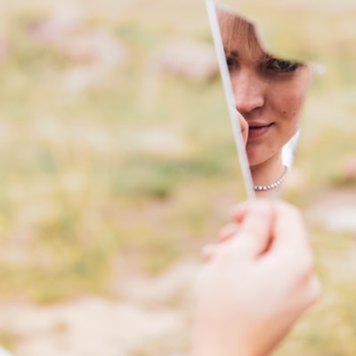 A woman looking at herself in the mirror with a calm, confident smile