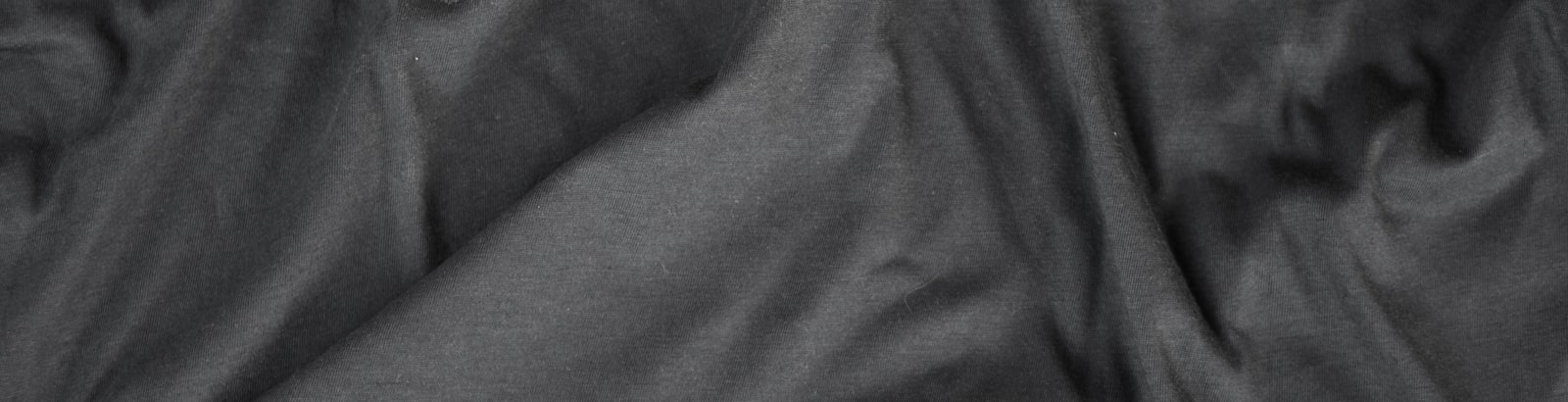 Close macro shot of undecorated knit fabric in the Black colorway used for blank practice jerseys.