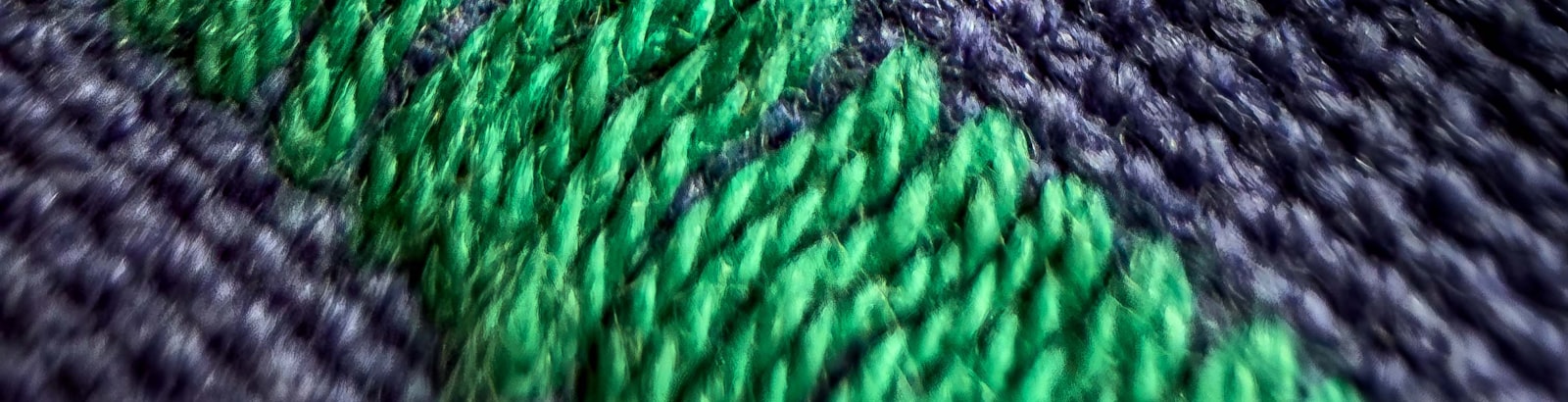Close macro shot of undecorated woven fabric in the Kelly Green colorway used for blank hockey pant shells.