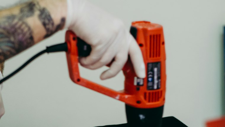 Full-color DTF transfer being peeled from a pressed logo on a polo sleeve
