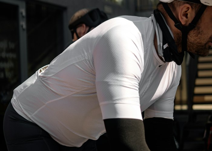 Player trying on a sample hockey jersey over shoulder pads to confirm fit