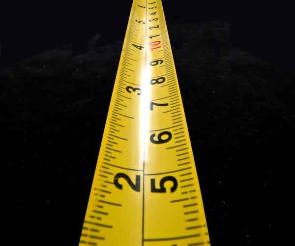 Youth hockey jersey laid flat on a table being measured with a tape