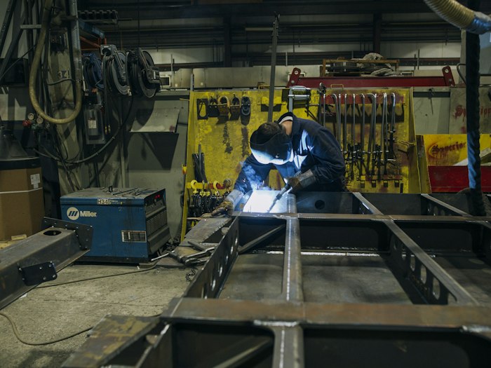 Tradesman in a mid-blue denim work shirt with a woven patch logo on the chest
