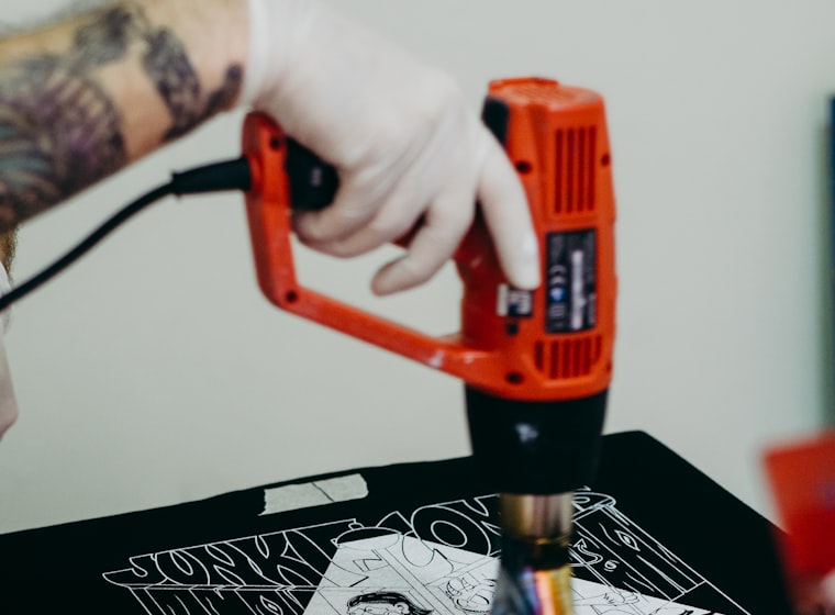 A decoration shop worker pressing a fictional team print onto an undecorated jersey