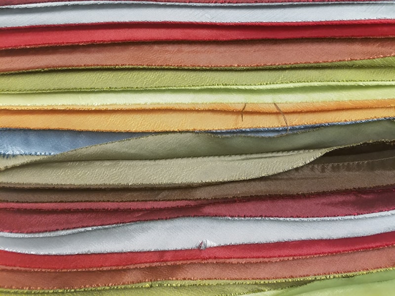 Physical fabric samples used as color references — the match is produced against the actual piece and confirmed on fabric