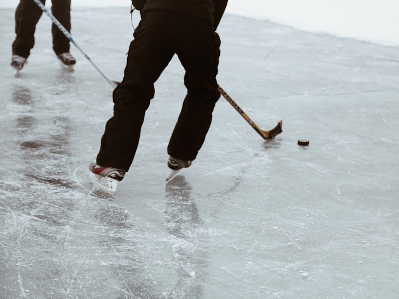A youth hockey team lineup at the rink boards wearing matched kits, pant shells coordinated with the jerseys