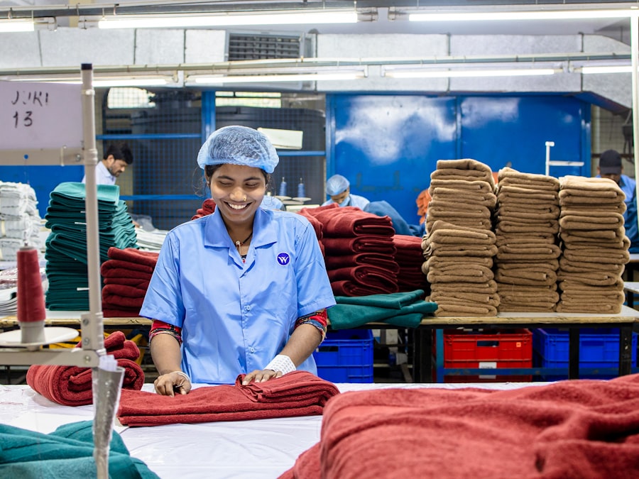 A worker checking a garment laid flat on the inspection table, face and hands visible