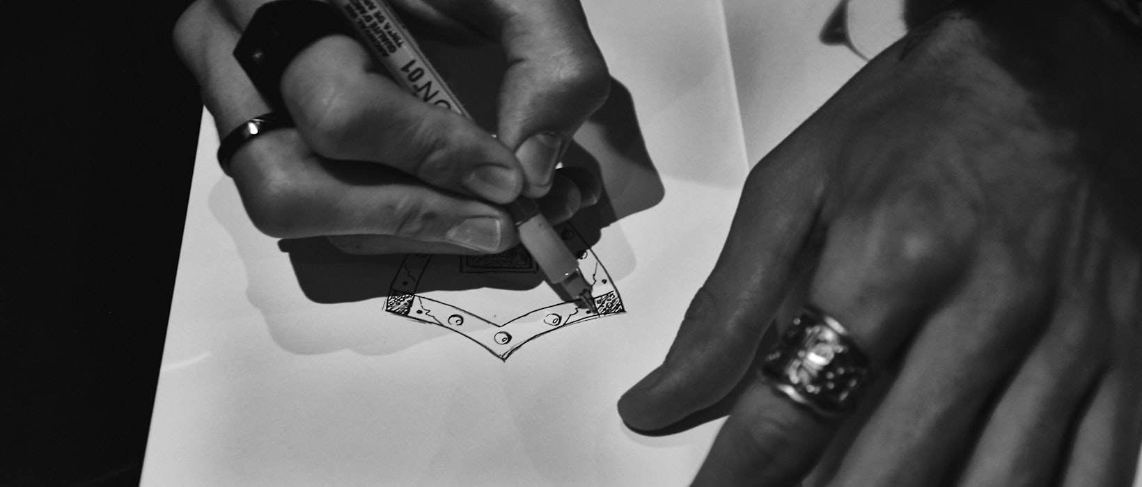 Hands drafting a graded garment pattern — the one pattern set behind every size on this chart