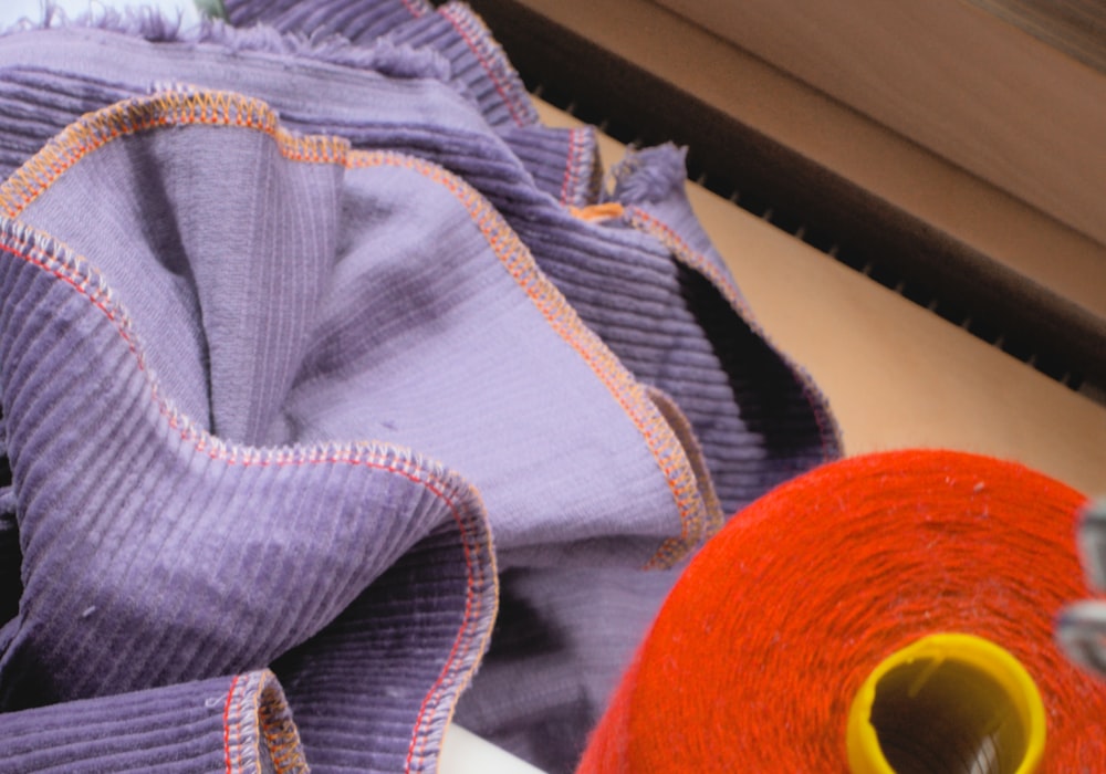 Sewer guiding hockey sock panels through a 4-thread overlock machine, face and hands visible