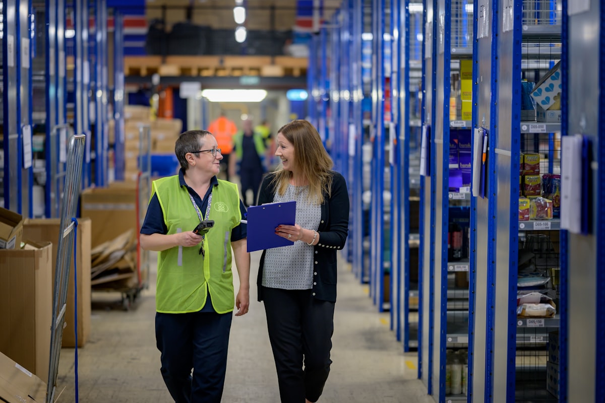 A warehouse parts shelf beside a wall-printer production line — the factory-direct support behind a distributor partnership