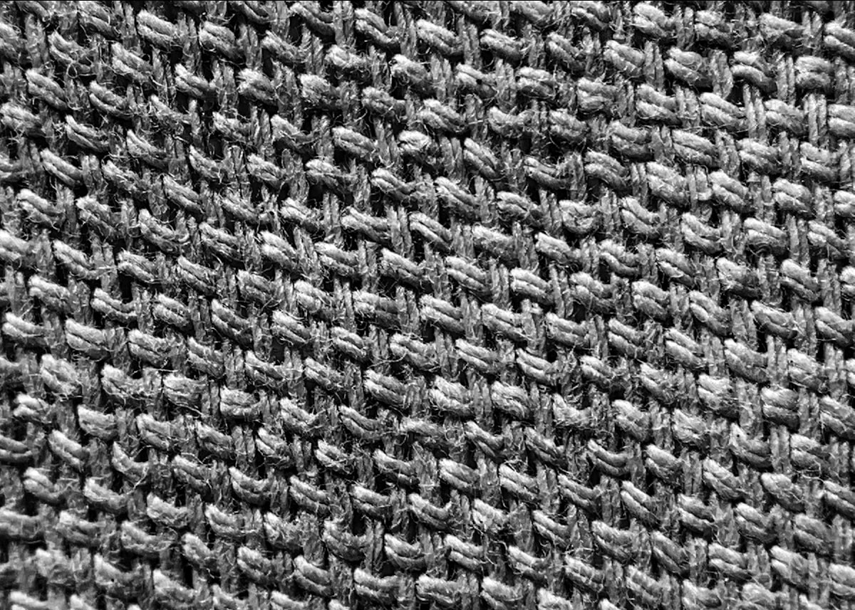 Close macro shot of mesh polyester fabric, open perforated weave with visible negative space.
