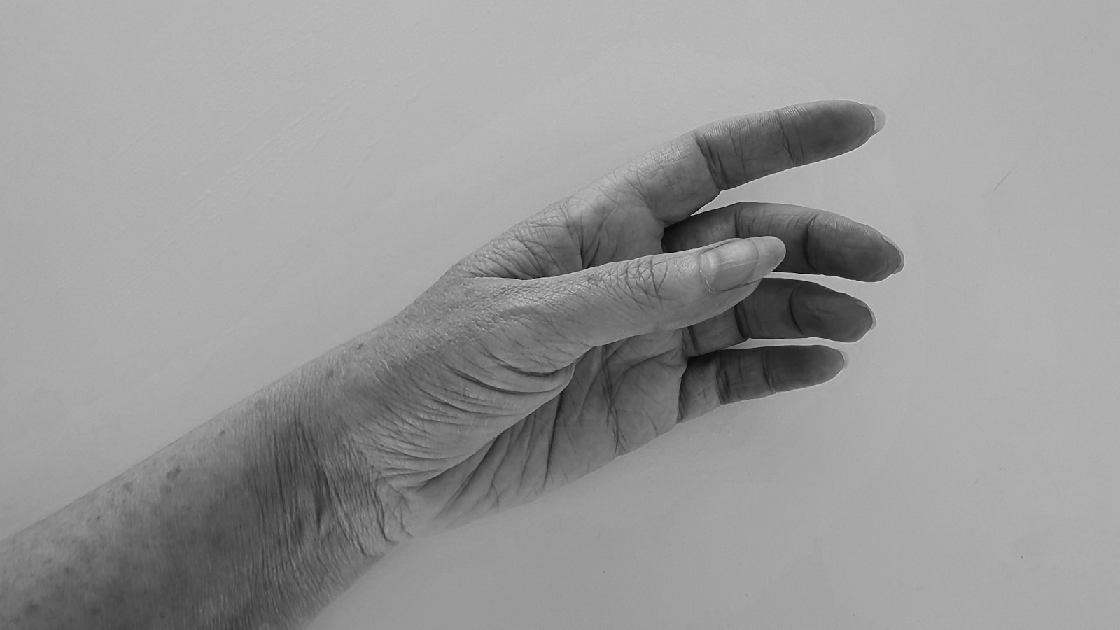 An elderly person pressing a large one-touch SOS pendant personal alarm at dusk as a carer responds nearby