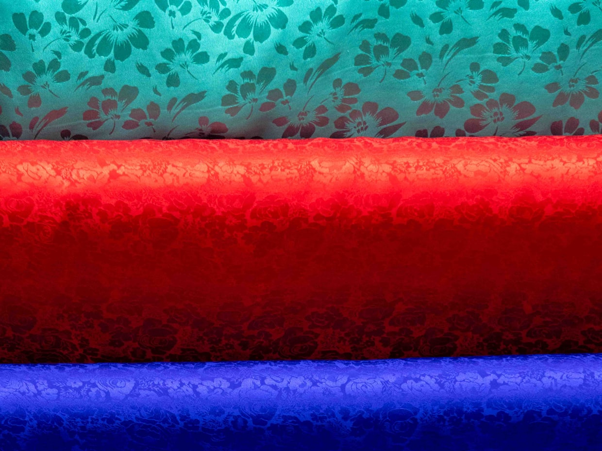 Registered polyester fabric stock — a reorder runs on the same fabric at the same weight as the run before it