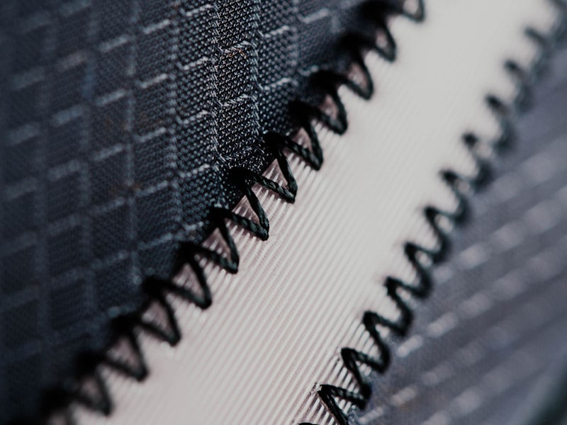 Close-up of seam stitching on technical performance fabric, representing the knee and lower-leg wear zone